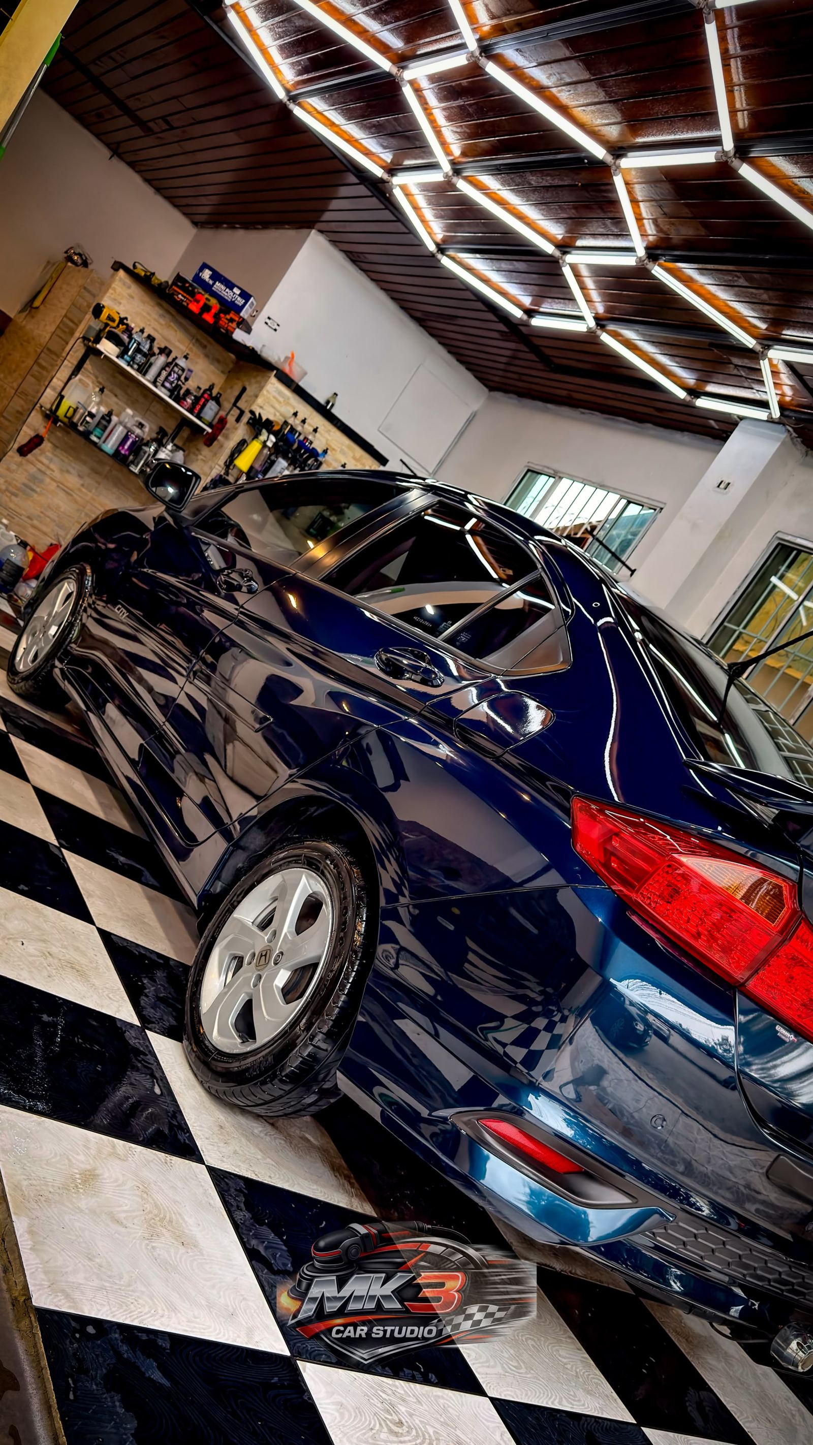 Sedã azul finalizado no estúdio da MK3 Car Studio, sobre o piso quadriculado